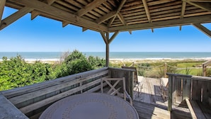 Une terrasse en bois offrant une vue sur la plage et l’océan.