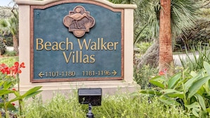 Un panneau indiquant l’emplacement de Beach Walker Villas, avec des flèches directionnelles et des numéros de téléphone.
