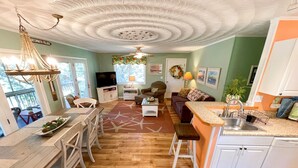 A spacious living area with a kitchen, dining table, and a cozy seating area. - Contentment: Spacious home, den, screened porch, marsh views. (Ocracoke)