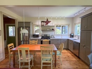 A kitchen with a dining table, chairs, a microwave, a stove, and a star decoration on the wall. - Olivella: Pet friendly, artistic, eclectic artwork, decks, porches. (Ocracoke)
