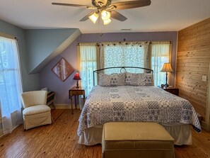 A bedroom with a bed, a chair, a lamp, and a ceiling fan. - Olivella: Pet friendly, artistic, eclectic artwork, decks, porches. (Ocracoke)