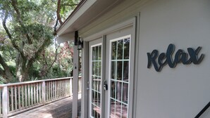 A wooden deck with a white door and a 'Relax' sign on the wall.