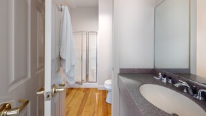 Une salle de bain avec un lavabo blanc, un grand miroir et un espace douche.