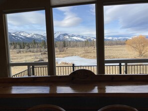 A room with a large window overlooking a mountainous landscape with a lake. - The Ponds-A Working Ranch (Hamilton)