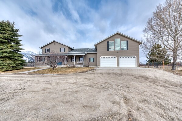A two-story house with a garage, a covered porch, and a driveway. - The Ponds-A Working Ranch (Hamilton)