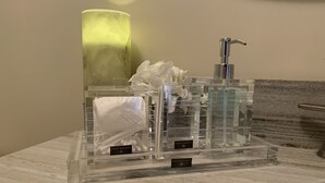 Un meuble-lavabo de salle de bain avec un distributeur de savon transparent en verre, une serviette blanche et une boîte de mouchoirs portant l’inscription « HÔTEL BALFOUR ».