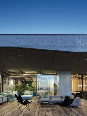 Un espace de détente extérieur moderne, doté d’un plafond en béton, d’un plancher en bois et de mobilier contemporain.