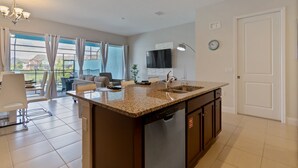 A modern kitchen with a granite countertop, stainless steel appliances, and a large window offering a view of the outdoors.