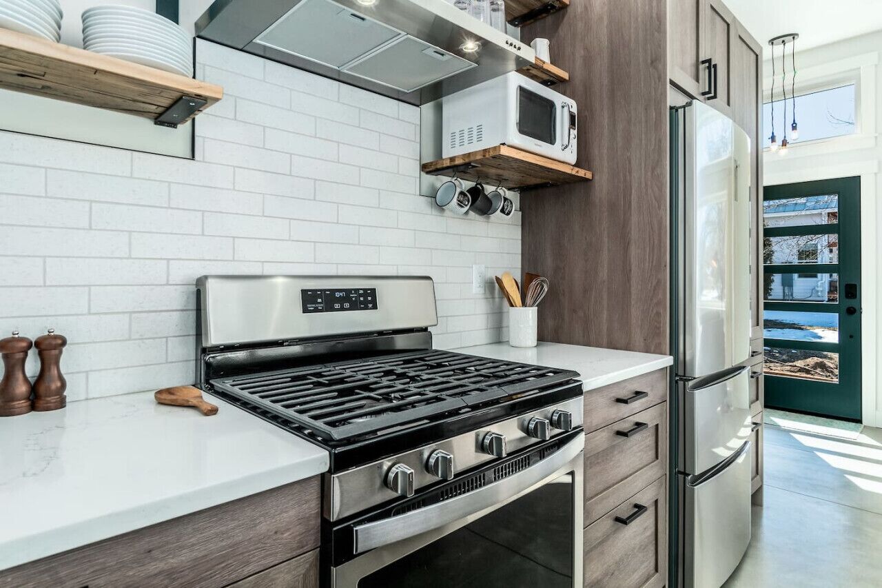 A modern kitchen with a gas stove, microwave, and refrigerator.