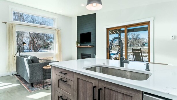A modern kitchen with a large island, built-in TV, and a view of the outdoors. - Colorado Modern Cabin (Fort Collins)