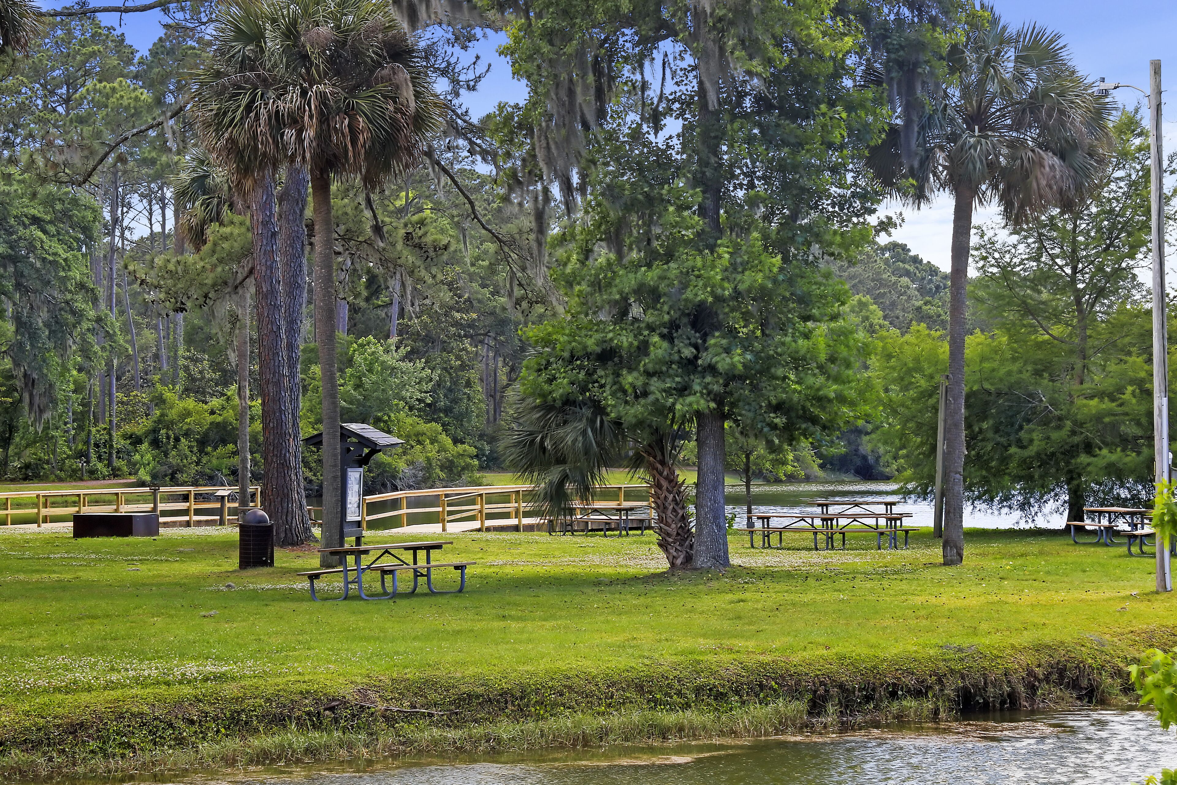 Un parc amb taules de picnic, un petit refugi i un estany.