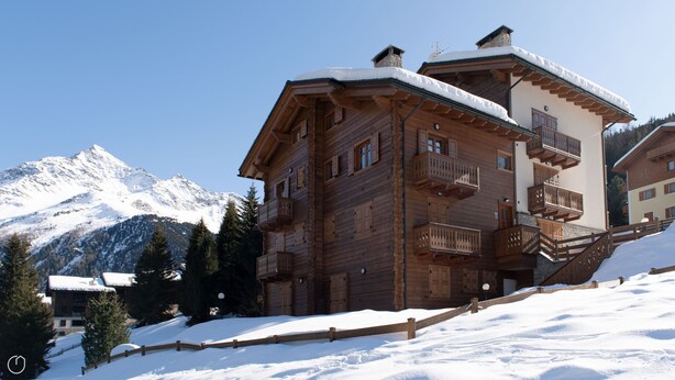 A wooden chalet with balconies, set against a snowy mountain backdrop. - Meralda 2 SCOIATTOLO (Valfurva)