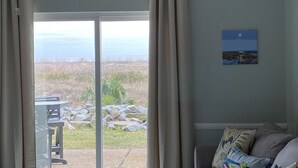 A room with a sliding glass door leading to a patio with a view of the ocean. - Ground Floor Ocean Front 2 Bedroom Villa, Golf Cart Included 413 Captain John Fripp (Fripp Island)