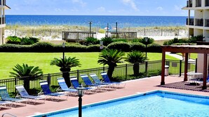 Zona de piscina con sillones de descanso y vista a la playa y al océano.