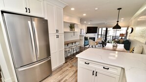 Una cocina moderna con armarios blancos, un refrigerador de acero inoxidable y una encimera de mármol.