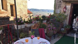 An outdoor dining area with a table set for two, surrounded by potted plants and a view of the mountains. - Casa de David - Apartment in Monsanto (Monsanto, Idanha-a-Nova)