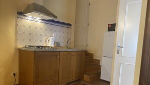 A compact kitchen with wooden cabinets, a gas stove, a sink, and a patterned backsplash. - Casa de David - Apartment in Monsanto (Monsanto, Idanha-a-Nova)