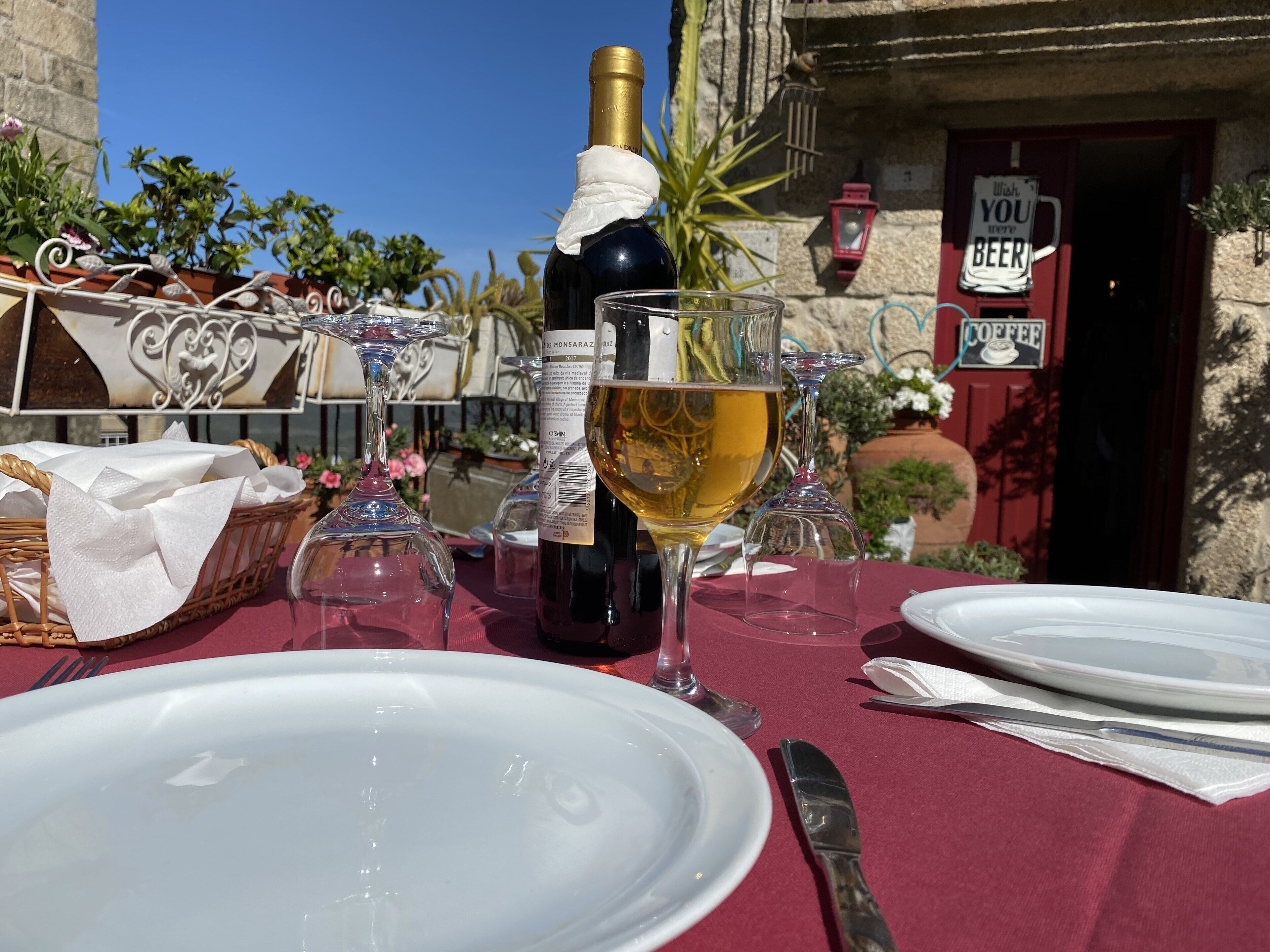 Una mesa preparada para una comida, con platos, una botella de vino y copas.