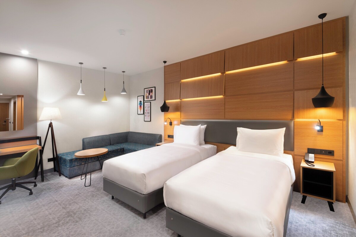 Een moderne hotelkamer met twee bedden, een bureau, een stoel en een bank.
