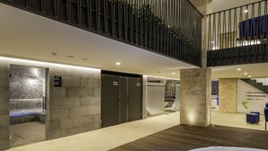 Ein moderner Innenraum mit einem zentralen Bereich, der eine Whirlpool, ein Duschbad und eine Sitzecke mit Blick auf eine Treppe bietet.