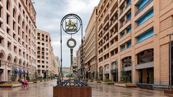Een ruim stadsplein met een centraal monument, omringd door meerverdiepingen met balkons en grote ramen.