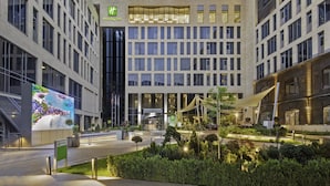 Ein Holiday Inn Hotel mit moderner Fassade, großen Fenstern und einem begrünten Innenhof.