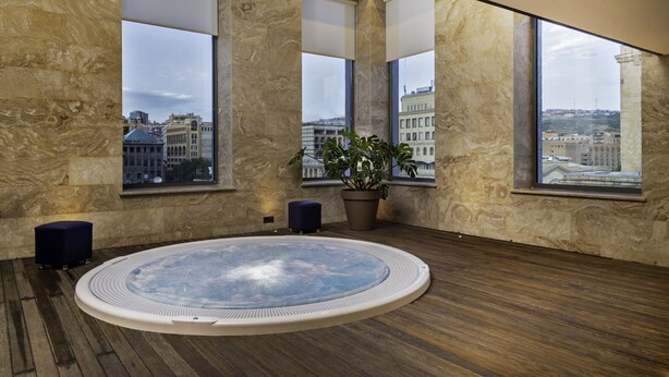 Ein moderner Wellnessraum mit Whirlpool, großen Fenstern und Blick auf die Stadt.