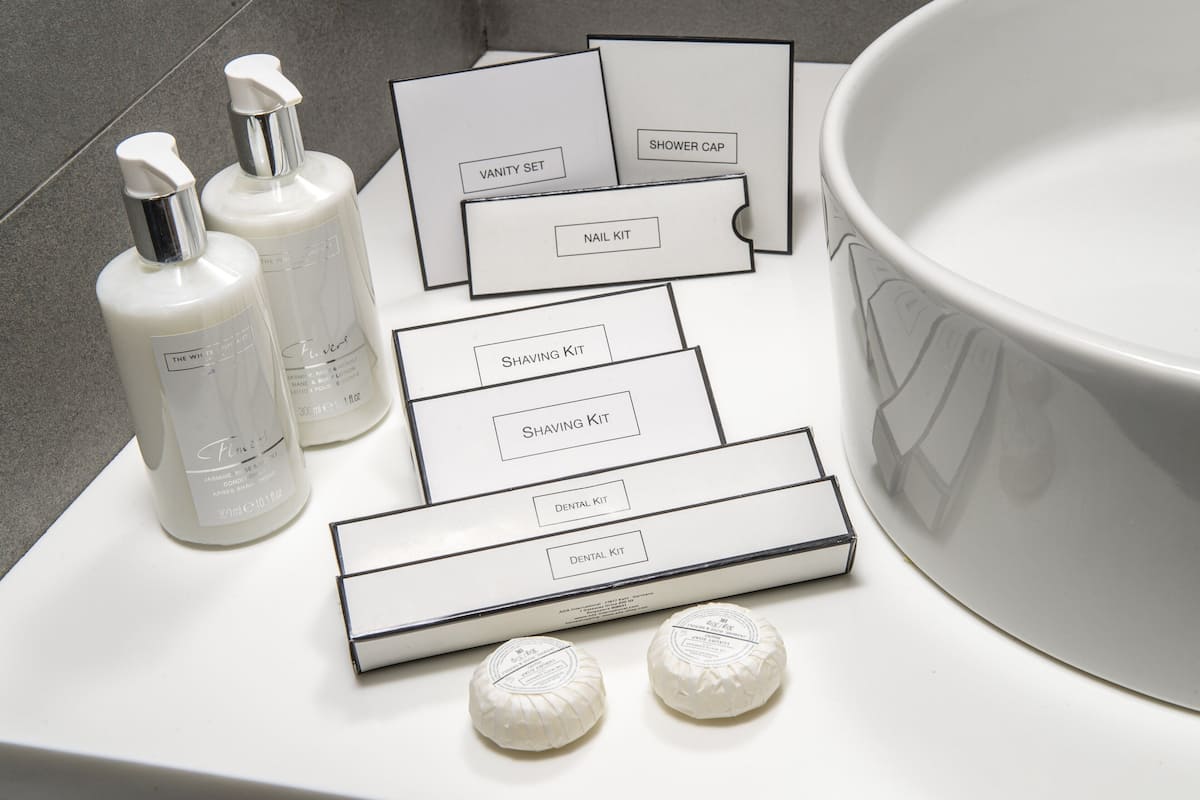 A bathroom vanity with a large mirror, a sink, and toiletries including a shaving kit, nail kit, and a vanity set.