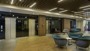 A modern office space with wooden flooring, contemporary chairs, and a reception area with glass doors.