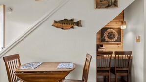 A dining area with a wooden table and chairs, a fish wall decoration, and a wooden wall with a 'get well' sign. - Dog friendly at the Seventh Mountain Resort! (Bend)