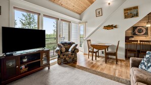 A spacious living room with a large flat-screen TV, a patterned armchair, and a dining area with wooden furniture. - Dog friendly at the Seventh Mountain Resort! (Bend)