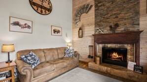A cozy living room with a fireplace, a leather sofa, and a clock on the wall. - Dog friendly at the Seventh Mountain Resort! (Bend)
