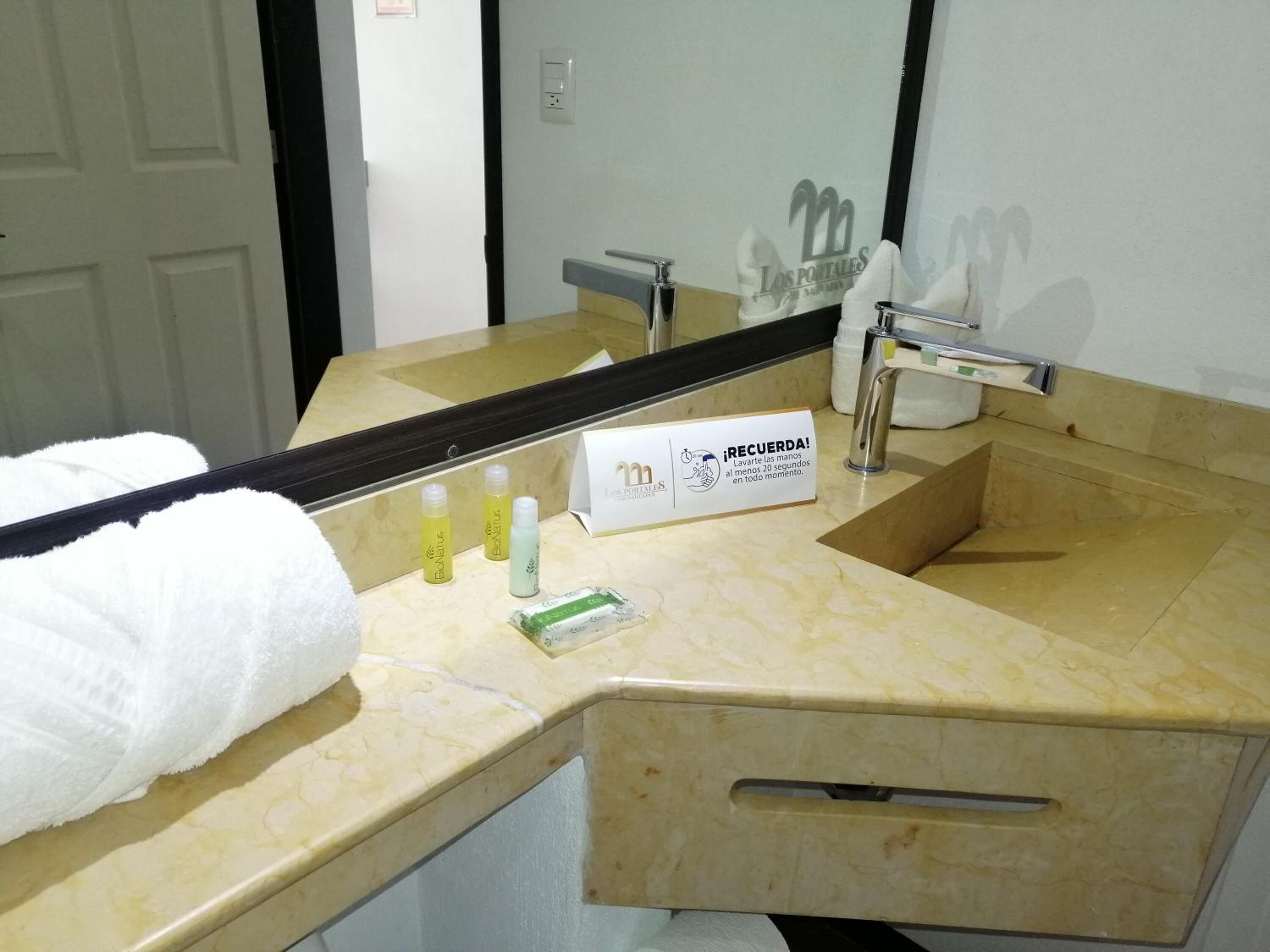 A bathroom with a marble sink, a towel, and toiletries.