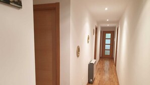 Un passadís amb terres de fusta, parets blanques i una porta al final.