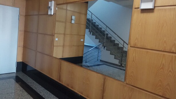 Passadís amb parets de fusta panelada, una secció amb mirall que reflecteix una escala i una porta a l'esquerra.