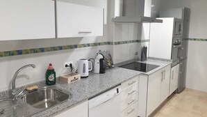 Cuina moderna amb armaris blancs, un rentaplat Bosch i un forn integrat, a més d'una pica d'acer inoxidable.