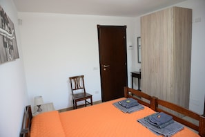 Un dormitorio con una cama, un armario de madera, una silla y un escritorio.