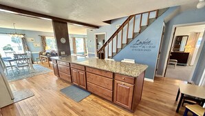 A spacious kitchen with wooden cabinets, a granite countertop, and a built-in stove. - Pier View: Cozy Second Row Beach Cottage with Sunroom, Great Views and Easy Beach Access (Brunswick)