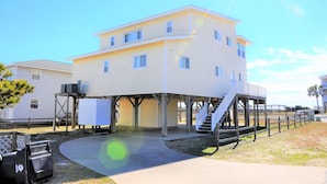 A two-story building with a covered patio area and a staircase leading to an upper level. - Pier View: Cozy Second Row Beach Cottage with Sunroom, Great Views and Easy Beach Access (Brunswick)