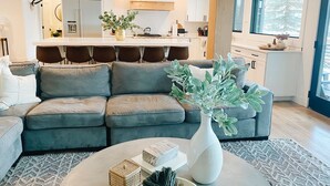 A modern living room with a grey sofa, a coffee table, and a vase with green foliage.
