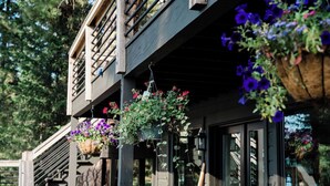 A wooden building with a balcony, hanging flower baskets, and a wooden railing.