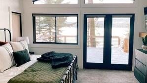 A bedroom with a bed, a window, and a view of a snowy landscape.