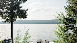 A beach with a dock, a boat, and a row of trees.
