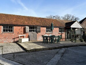 A brick building with a small patio area, a table with chairs, and a gate.