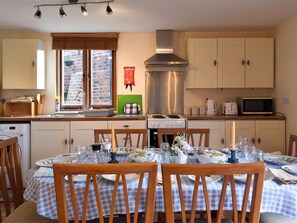 A kitchen with a dining table set for four, a stove, a microwave, and a sink.