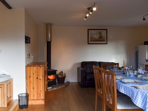 A cozy living room with a fireplace, a dining area with a table set for two, and a comfortable sofa.