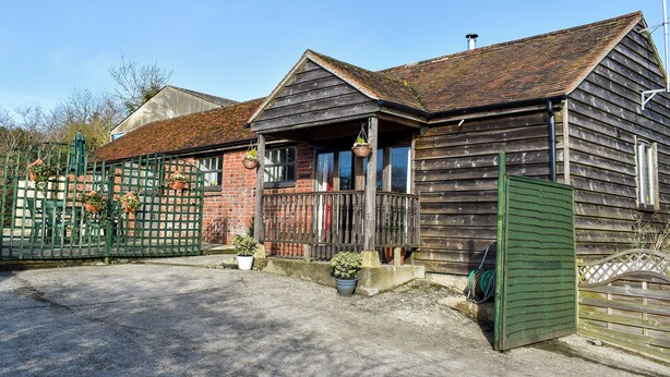 Ein Holzhaus mit einer Veranda, einem grünen Tor und Blumentöpfen.