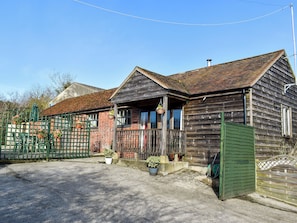A wooden house with a porch, a green gate, and potted plants.