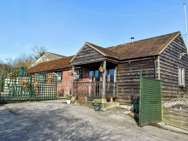A wooden house with a porch, a green gate, and potted plants.