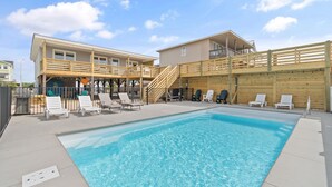 A swimming pool with sun loungers and a wooden deck with stairs leading to a building. - Newly Renovated, 4 bed 2 bath, Pet Friendly Oceanfront w/ a Pool! (Brunswick)